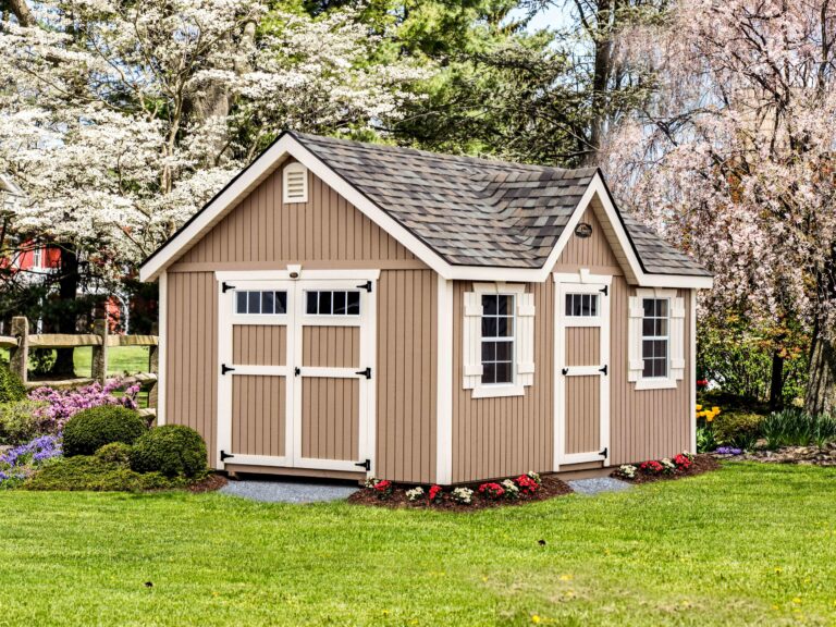 Beige and white garden shed with white-trimmed double doors and windows beneath brown shingled roof. Just one of the sheds we deliver to Midland, MI