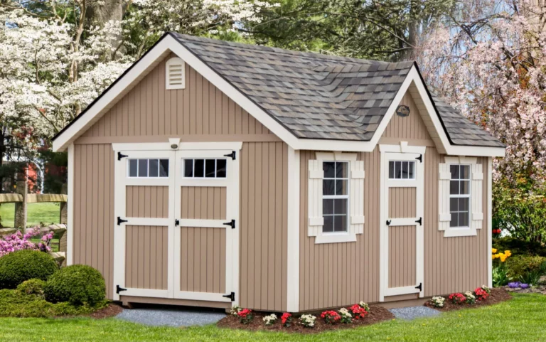 Lofted barn with a brown metal roof and decorative wooden doors situated in a green yard.